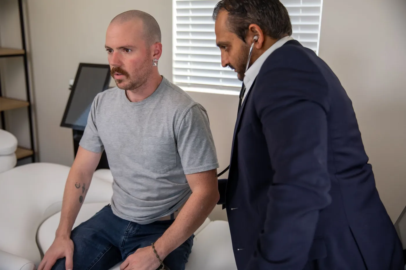 Dr. Bhavesh Patel listening to a patient's breathing during an exam at the Rx2BFIT office