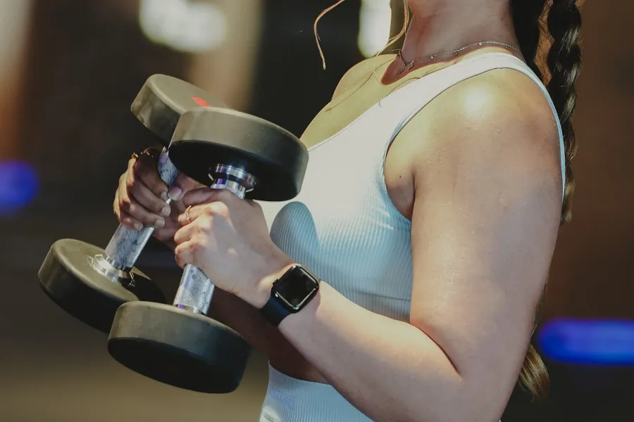 A woman holding a pair of dumbbells at her sides