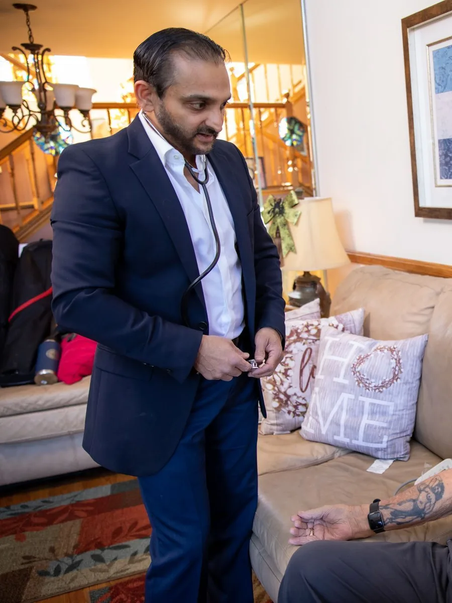 Dr. Bhavesh Patel checking an older patient's blood pressure during a home visit
