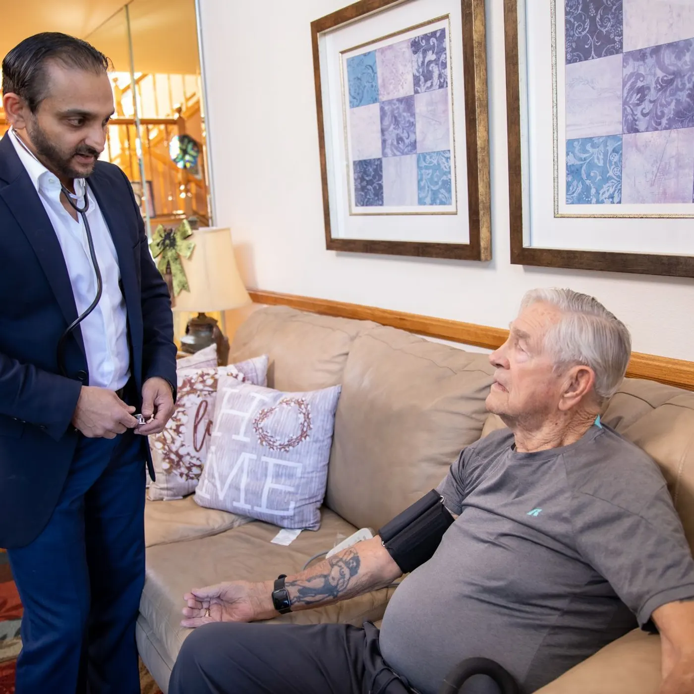Dr. Bhavesh Patel checking an older patient's blood pressure during a home visit