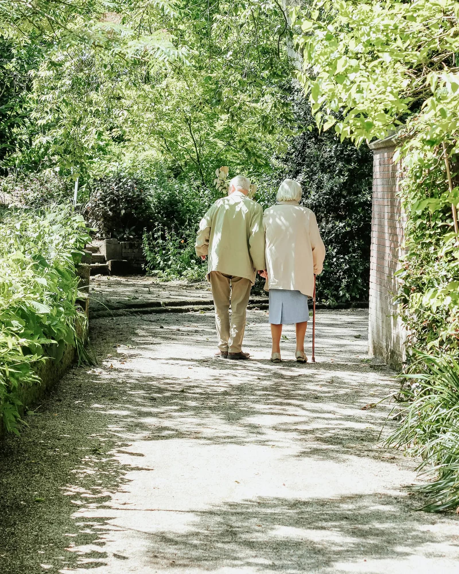 An older couple walking together along a garden path