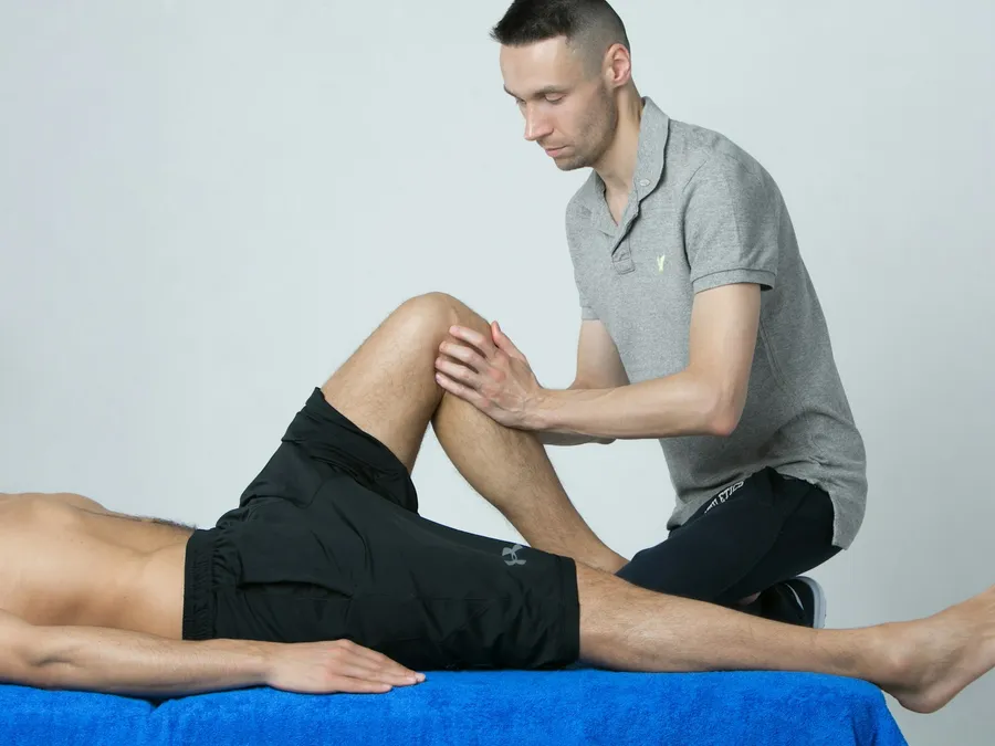 A therapist pressing on the bent knee of a patient lying down