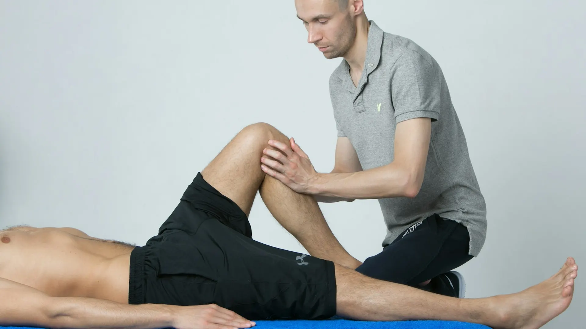 A therapist working on a patient's knee on a treatment table