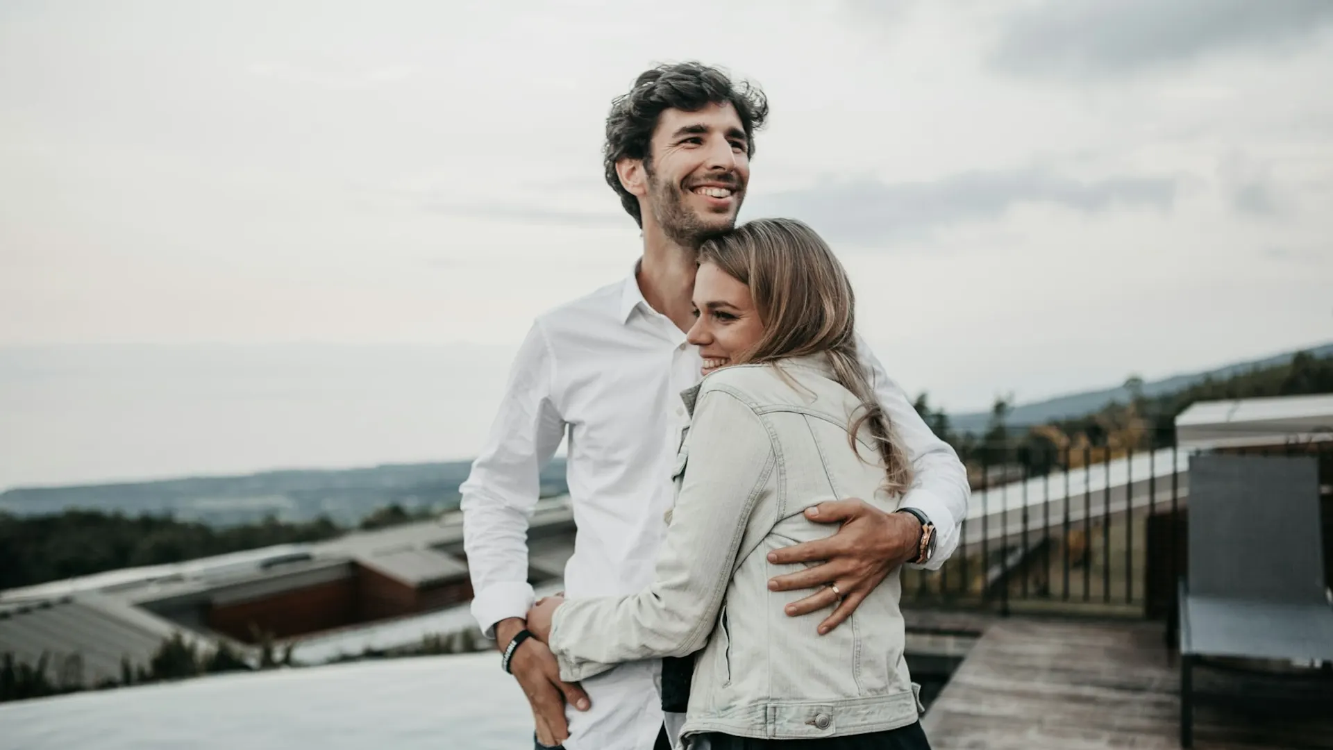 A couple hugging and smiling outdoors under an overcast sky