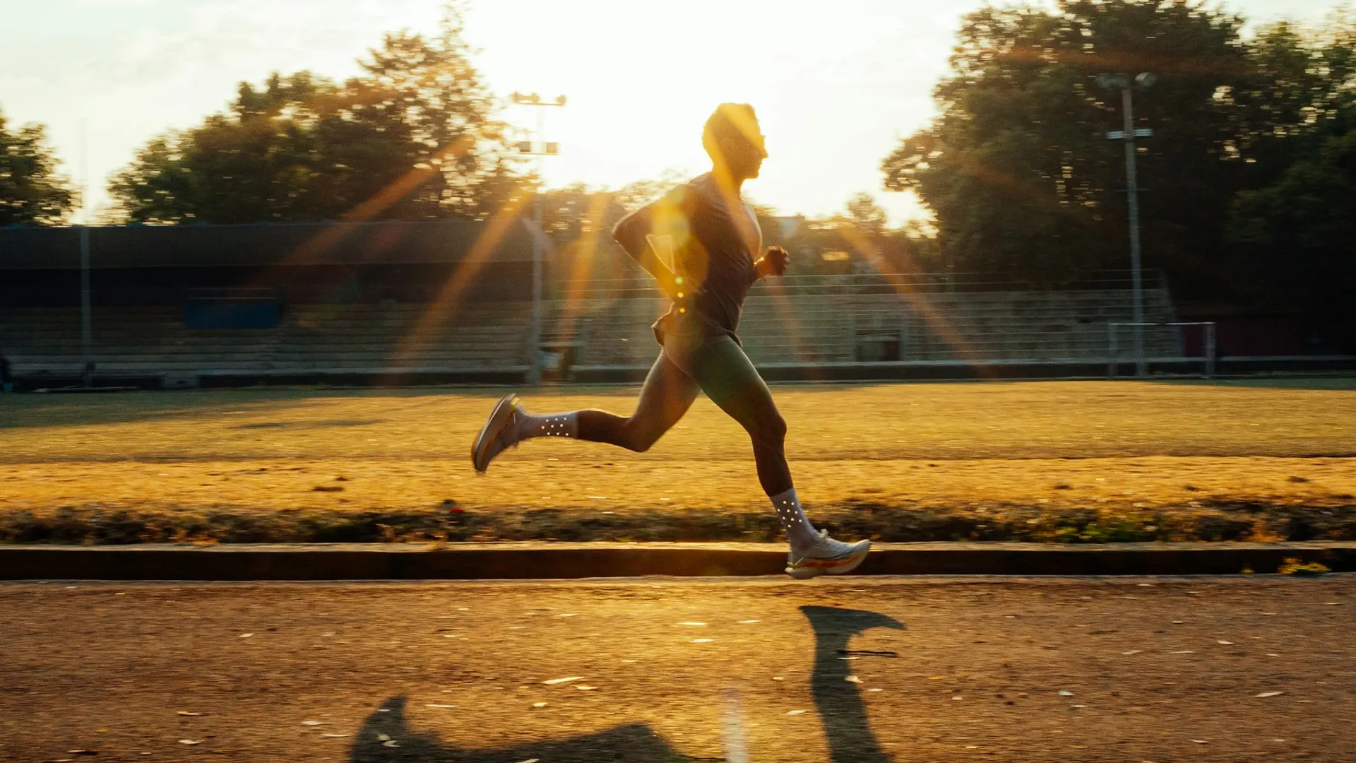 A runner mid-stride on a track at golden hour