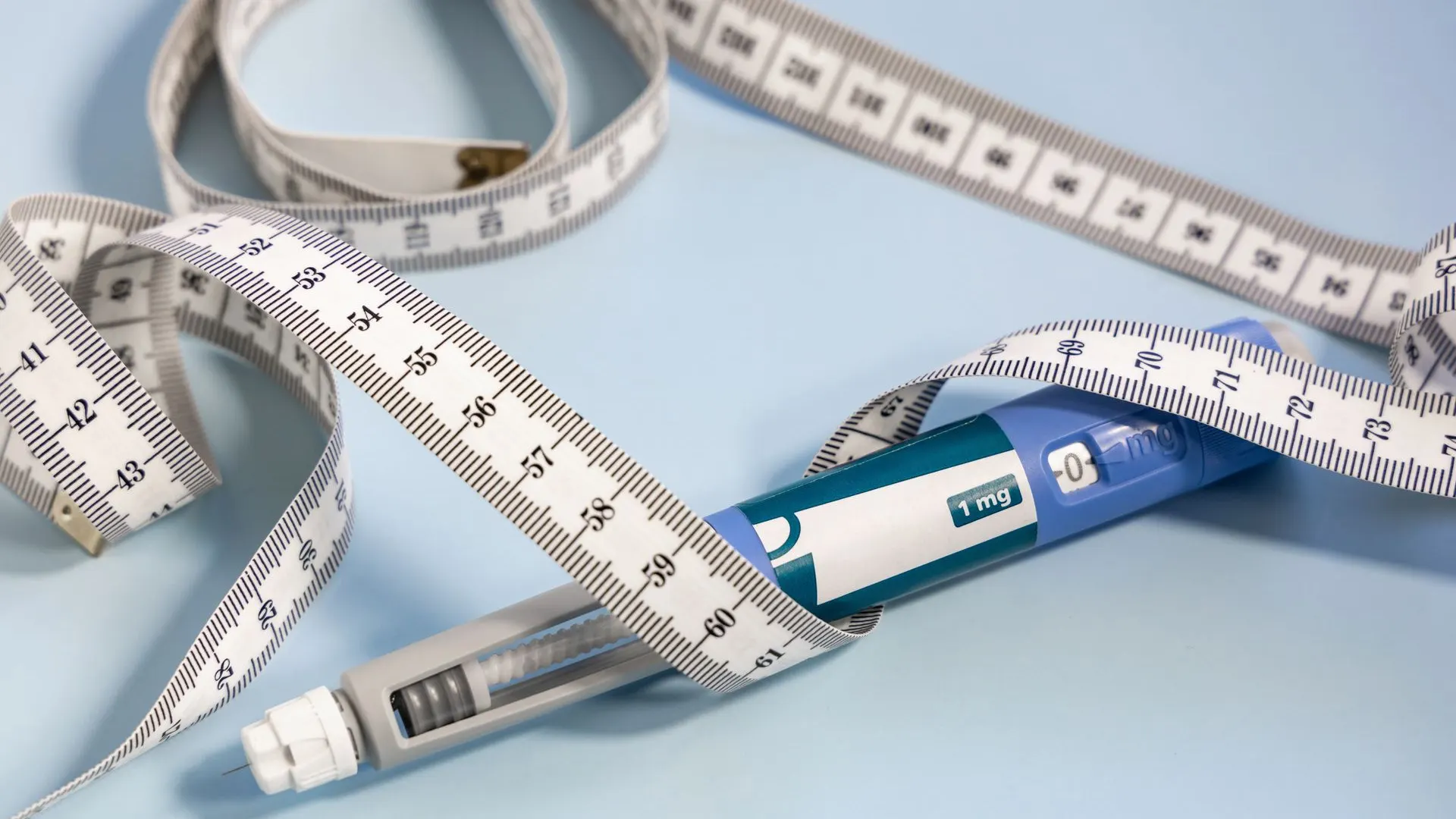 An injection pen lying among loops of a measuring tape