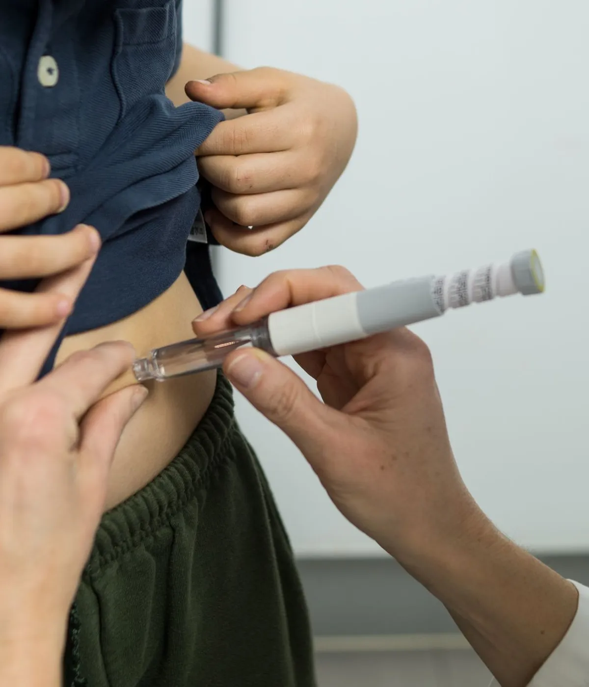 A clinician giving a subcutaneous injection into a patient's abdomen