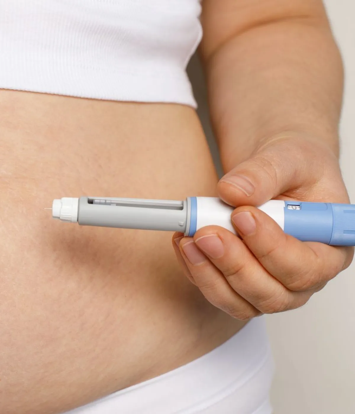 A person holding a GLP-1 injection pen at their waist