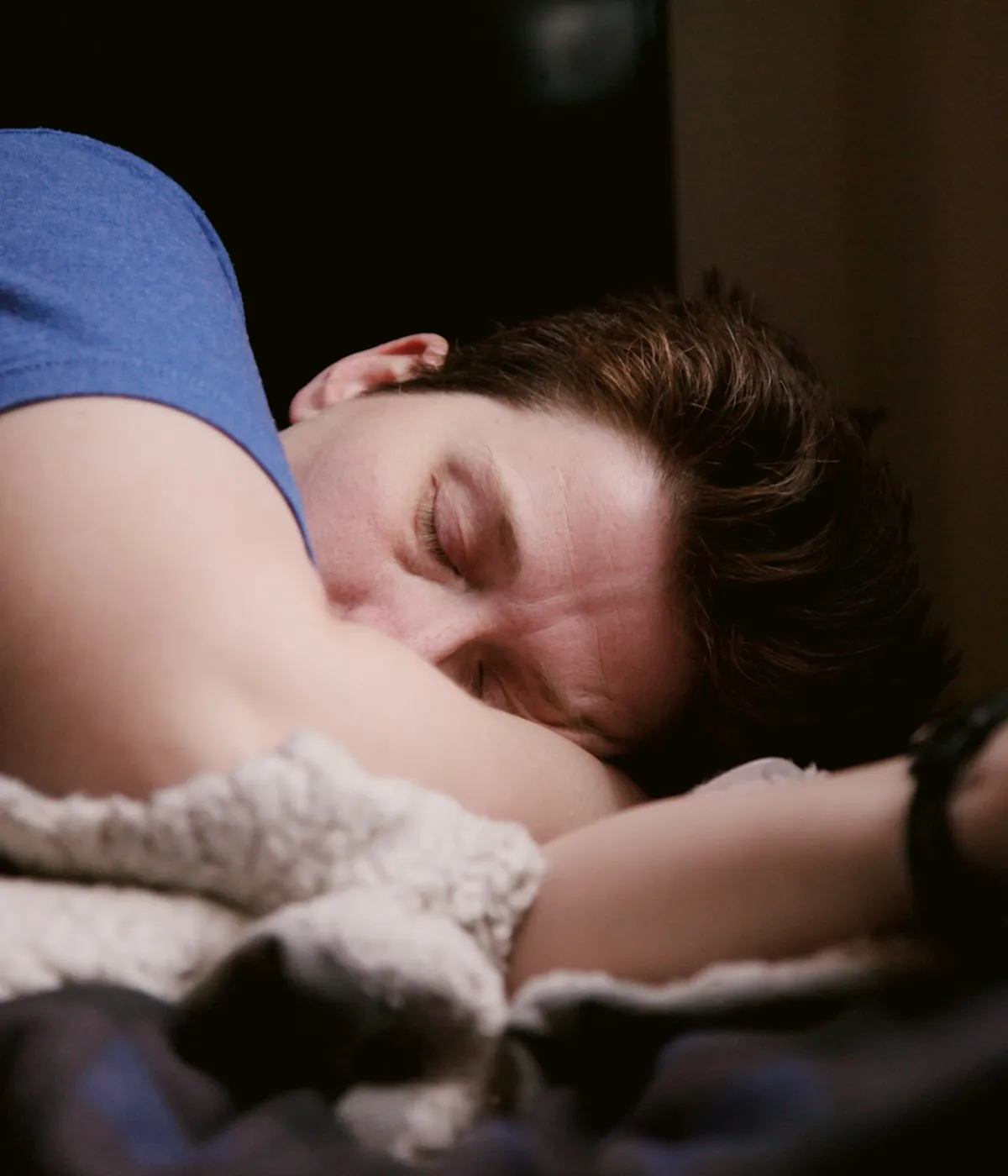 A man asleep on his side in a dim bedroom