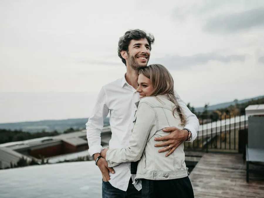 A smiling couple embracing on a rooftop terrace