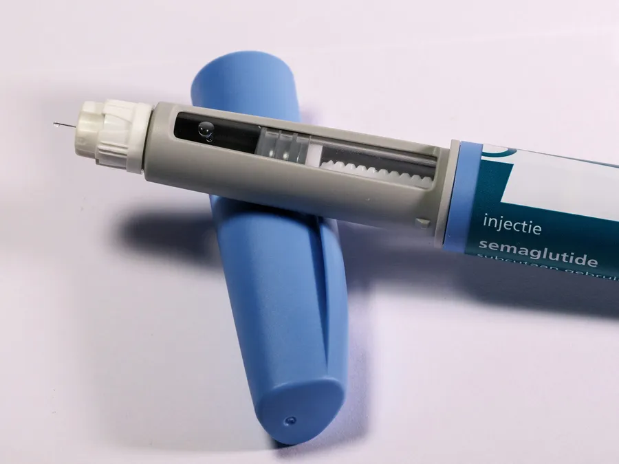 A semaglutide injection pen resting across its blue cap