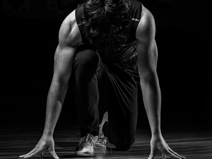 A sprinter crouched in a starting position, in black and white